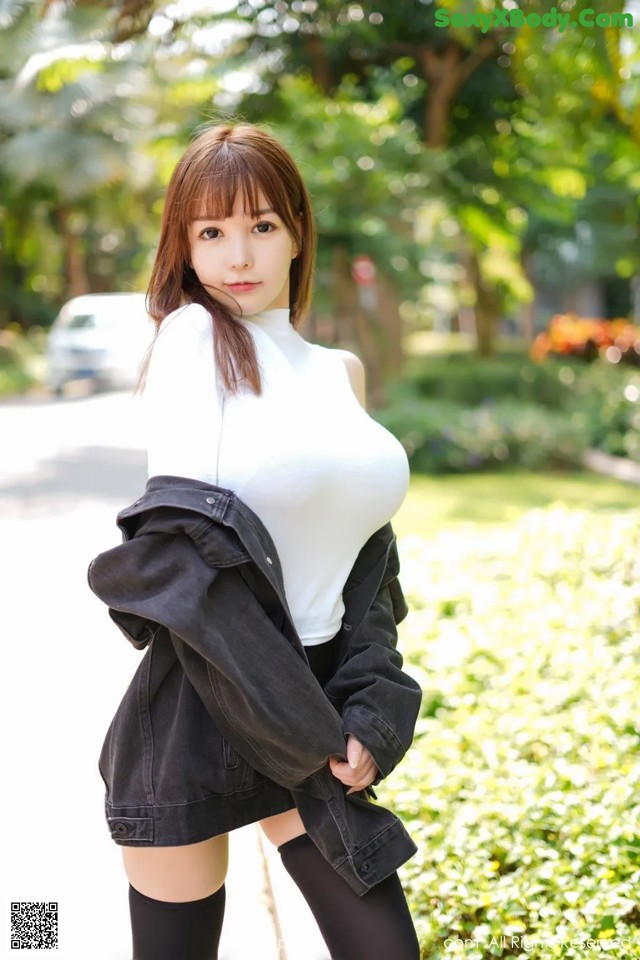 A woman in a white shirt and black skirt posing for a picture.