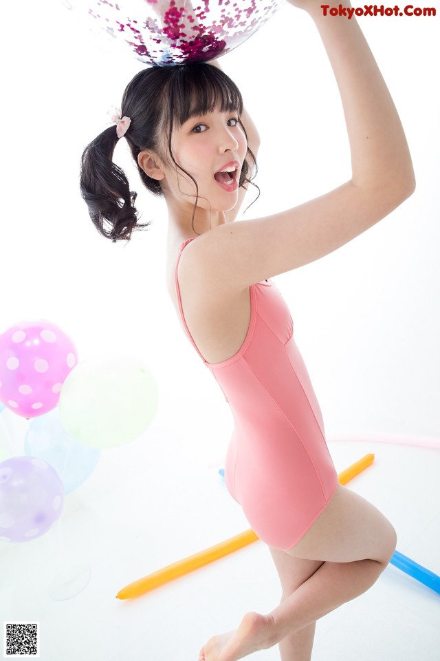 A young girl in a pink leotard holding a balloon.