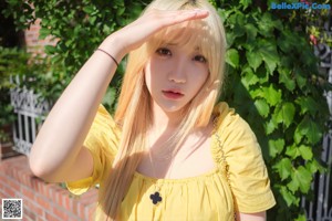 A woman in a yellow dress taking a selfie.