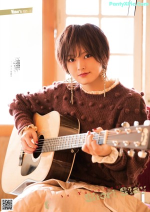 A woman in a blue and white striped shirt is posing for a magazine.