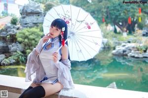 A woman sitting on the steps of a building holding a blue umbrella.