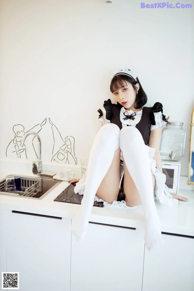 A woman sitting on top of a kitchen counter.