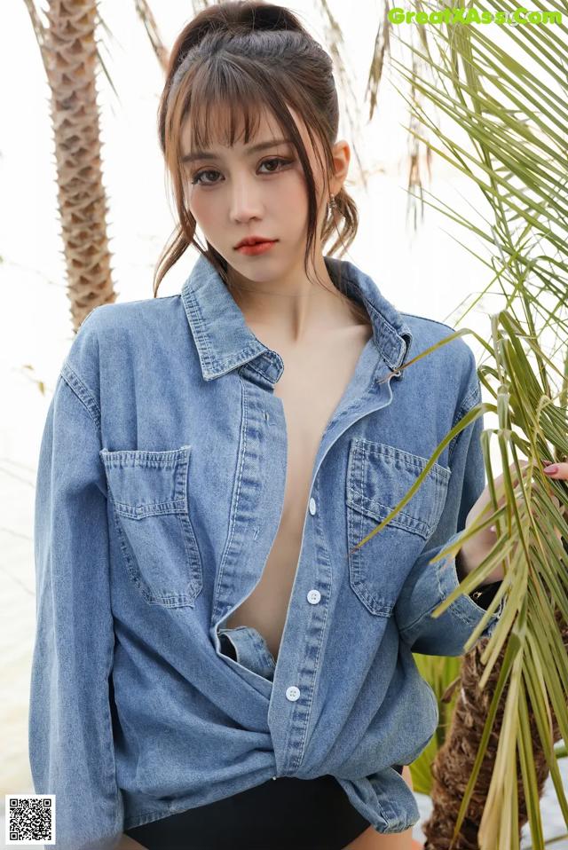 a woman in a denim shirt and black shorts posing for a picture