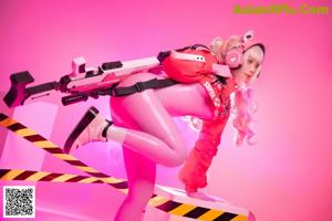 A woman in a pink outfit holding a gun.