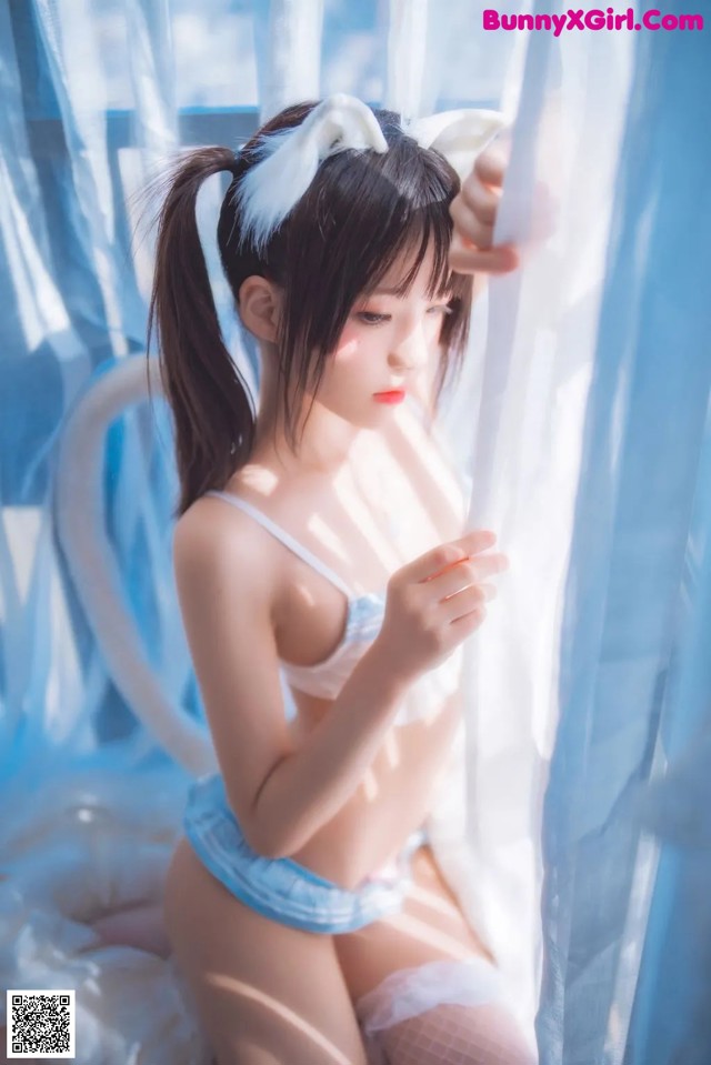 A woman in a blue lingerie sitting on a bed.