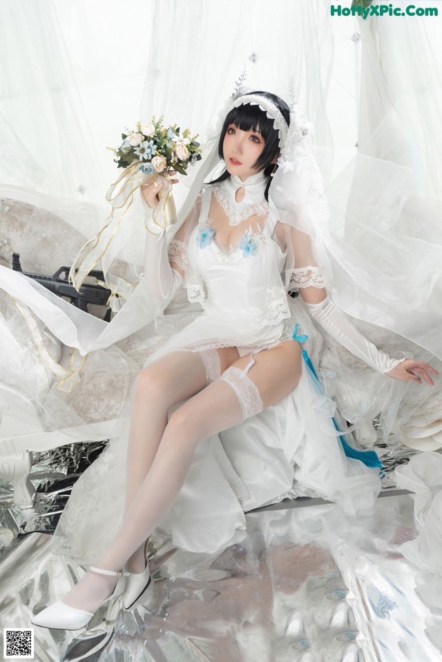 A woman in a wedding dress sitting on a bed.