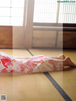 A woman in a kimono holding a pink pinwheel.