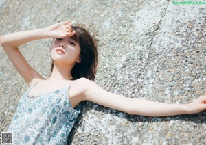 A woman sitting on the floor wearing a sheer white shirt.