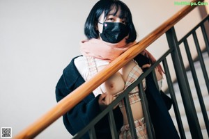 A woman wearing a face mask sitting on the ground.