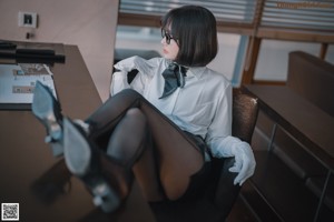 A woman sitting on a brown couch with her back to the camera.