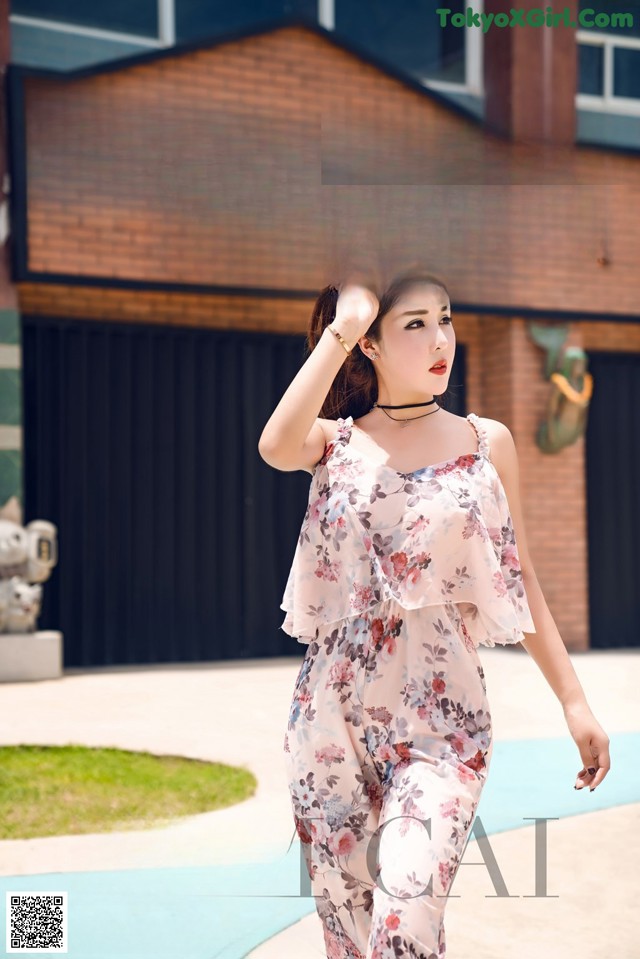 A woman in a floral dress is walking in front of a store.