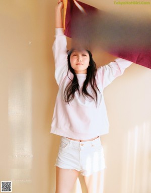 A woman in a white shirt and black pants posing for a magazine.