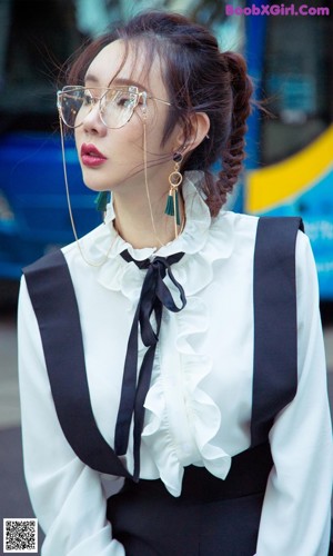 A woman in a white shirt and blue skirt leaning against a railing.