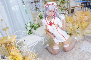 A woman in a white nurse outfit sitting on a white chair.