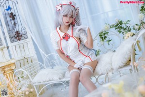 A woman dressed as a nurse sitting on a white couch.