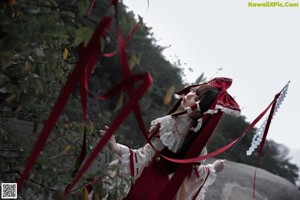 A woman in a red and white dress holding a fan.