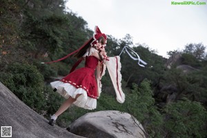 A woman in a red and white dress laying on a rock.