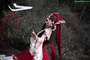 A woman in a red and white dress standing on a rock.
