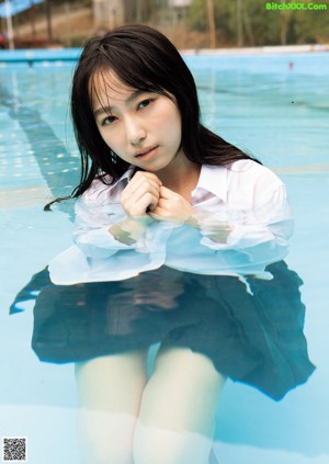 A woman in a white shirt and black skirt sitting in a pool.