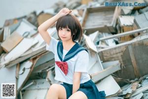 A woman in a school uniform sitting on a pile of rubble.