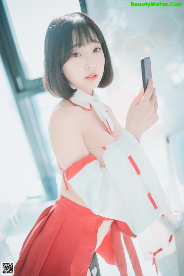 A woman in a red and white outfit holding a cell phone.