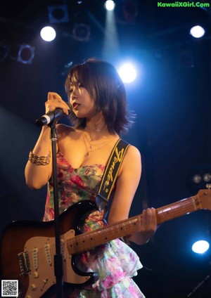 A naked asian woman in a purple skirt on a bed.