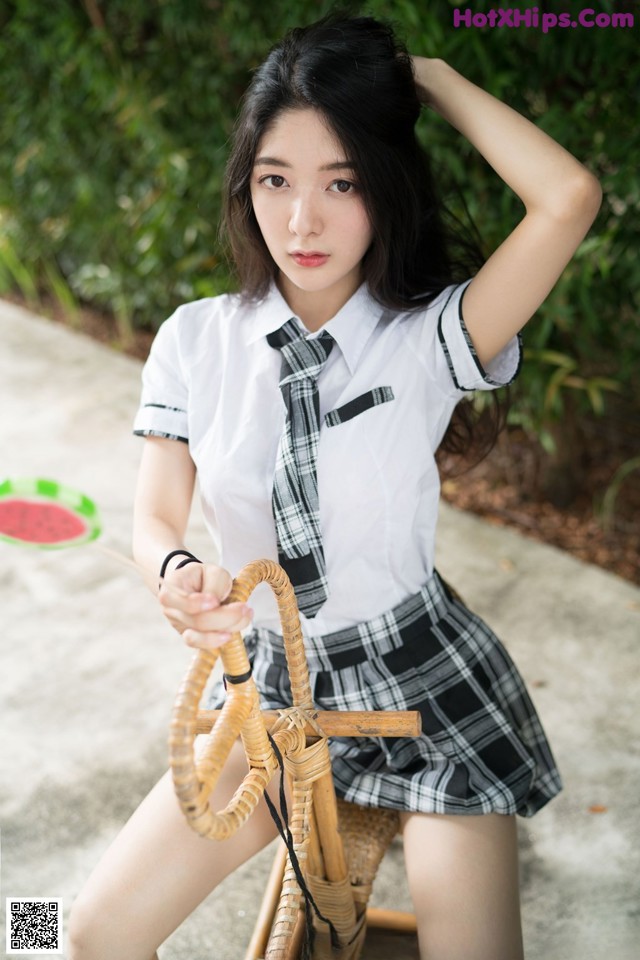 A woman in a school uniform sitting on a chair.