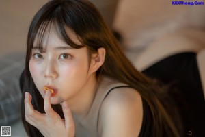 A woman sitting at a table eating a piece of food.