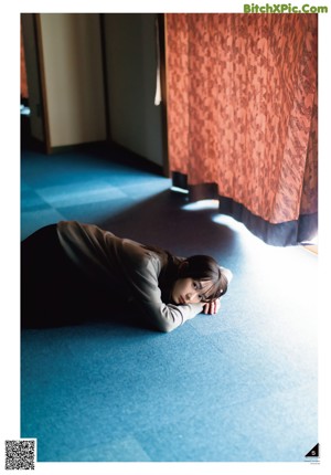 A woman laying on a red carpet with her head resting on her hands.