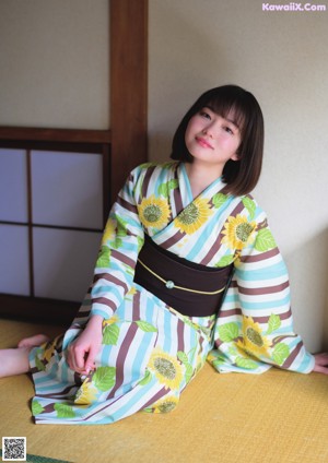 A woman in a kimono and a straw hat posing for a picture.