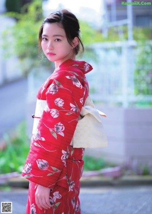 A woman in a red kimono is posing for a picture.