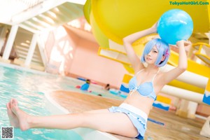 A woman in a blue bikini sitting next to a palm tree.