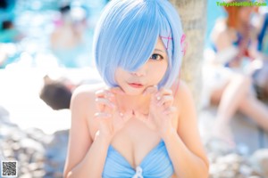 A woman in a blue bikini sitting next to a pool.